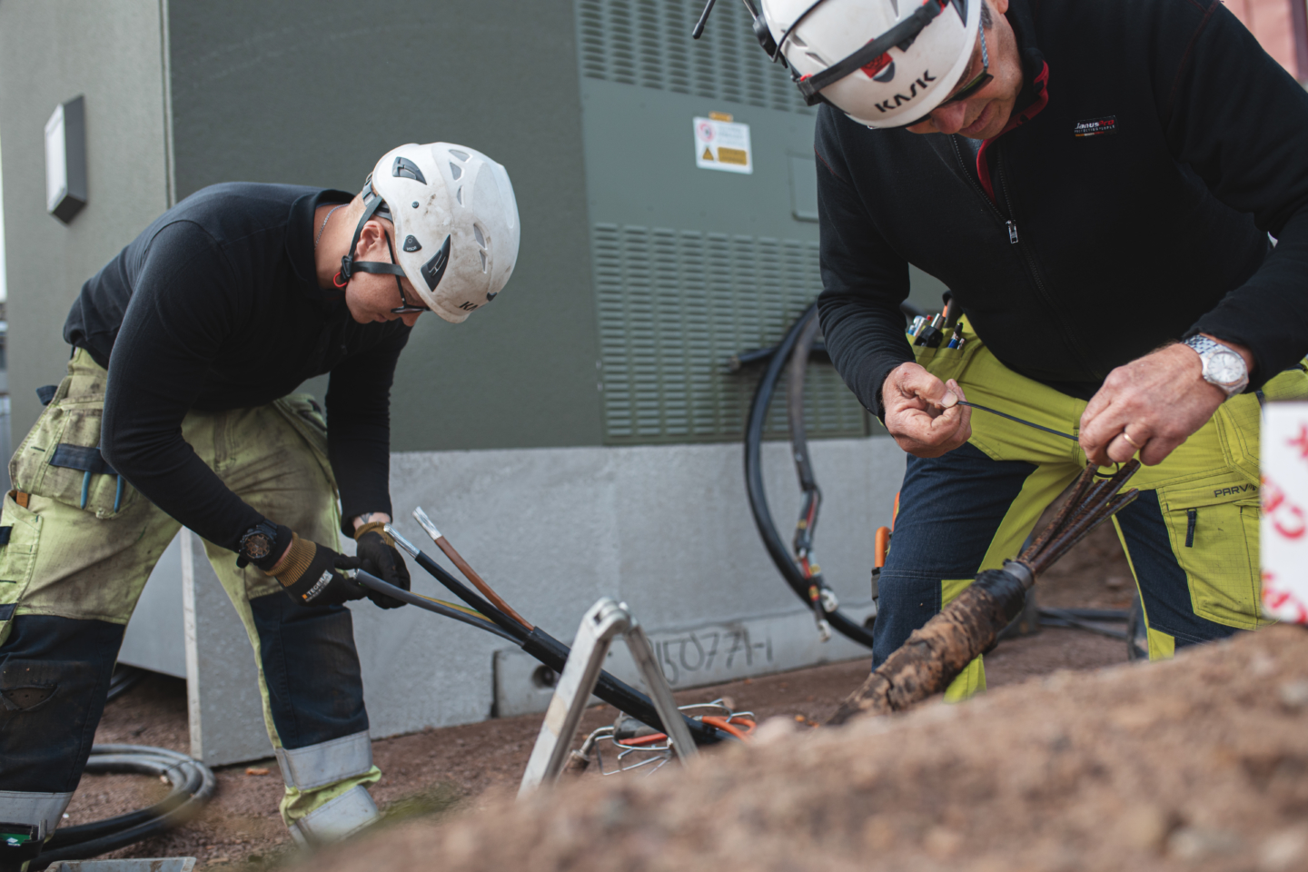 Elektriker arbetar med högspänningskablar vid en nätstation.